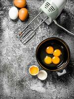 horneando antecedentes. mezcla huevos con un mezclador a hacer un masa. foto