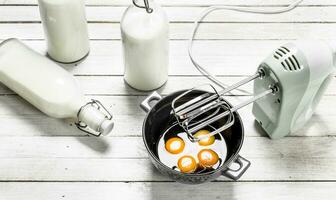 Baking background. Fresh eggs with a mixer. photo