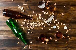 Four beers with pistachios on a wooden table. photo