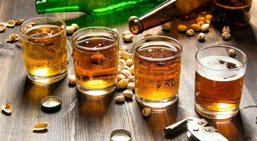 Four beers with pistachios on a wooden table. photo