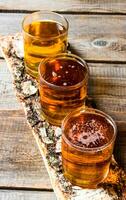 Three beers on birch stand. On a wooden table. photo