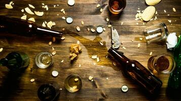 en el proceso de fiesta - derramado cerveza, botella tapas y sobrante papas fritas en el mesa. foto
