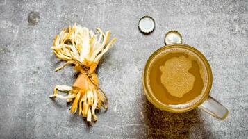 Glass of beer and salty cheese on stone background. photo