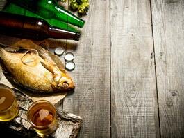 Smoked fish and fresh beer on a wooden table. Free space for text. photo