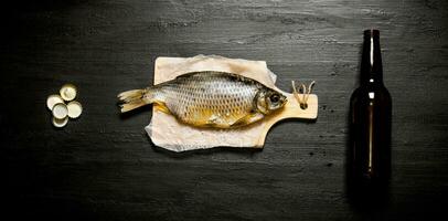 Dried fish and beer bottle on the black board. photo