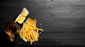 Fresh beer and fries with mustard sauce on the chalkboard. Free space for text. photo