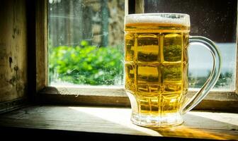 Glass of fresh beer on old wooden window sill . photo