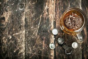 Fresco cerveza en un vaso con tapones y un botella abrelatas. foto