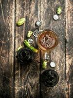 glass of fresh beer with bottles and cork. photo