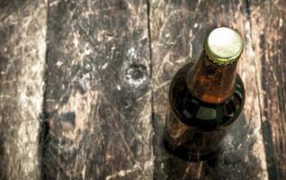 bottle of fresh beer. On wooden background. photo