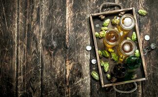 Fresh beer in glasses with green hops on an old tray. photo