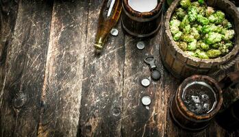 Beer in a wooden mug with green hops. photo