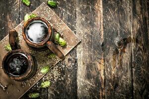 Beer in a wooden mug with green hops. photo