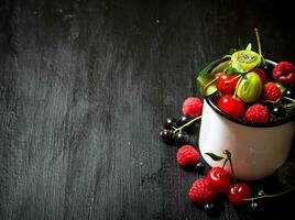 Berries in a mug. On black wooden background. photo