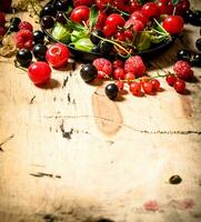 Wild berries in the old plate. On wooden table. photo