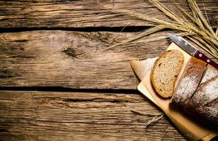 Fresh bread with ears of rye. On wooden table. photo