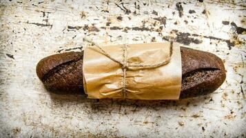 Rye bread wrapped in paper. On rustic background. photo