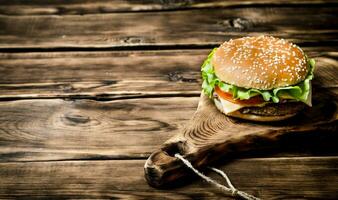 delicious Burger with meat , cheese and vegetables on wooden Board. photo