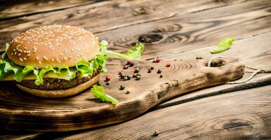 Burger on an old wooden Board with spices. photo