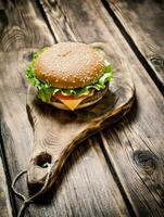 delicious Burger with meat , cheese and vegetables on wooden Board. photo