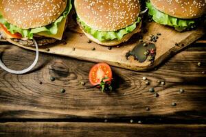 Three finished Burger with meat and vegetables on wooden stand. photo