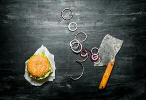 Burger with onion rings and an old hatchet.  Top view. photo