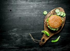Burger on a cutting Board with cucumber and herbs. photo