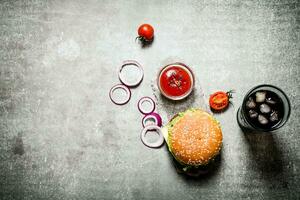 hamburger with tomato ketchup and soda on stone table. photo