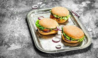 Burgers with beef and fresh vegetables on a steel tray. photo