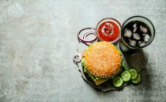 hamburger with tomato ketchup and soda on stone table. photo