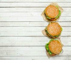 Burgers with beef, cheese and vegetables on paper. photo