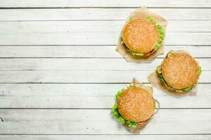 Burgers with beef, cheese and vegetables on paper. photo