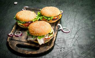 Burgers with beef, vegetables and sweet onions on an old board. photo