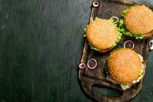 Burgers with beef, vegetables and sweet onions on an old board. photo