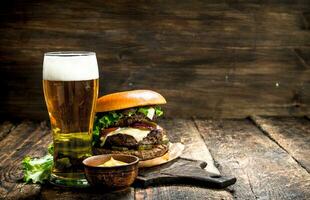 rápido alimento. un grande hamburguesa con carne de vaca y un vaso de cerveza. foto