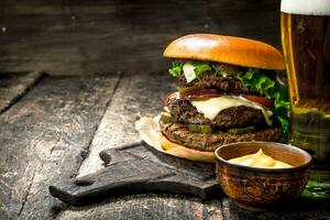 Fast food. A big burger with beef and a glass of beer. photo