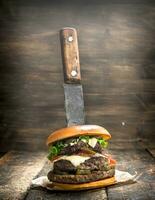 Fast food. A fresh burger made from beef and vegetables with a large knife. photo