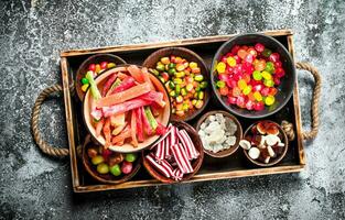 sweets candy, candied fruits with marshmallow and jelly on a wooden tray. photo