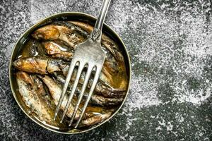 Canned sprats in tin can with fork. photo