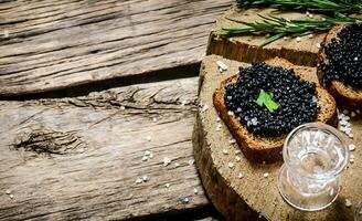 Sandwiches with black caviar and vodka. photo