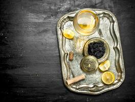 Black caviar with white wine on the old tray. photo