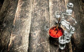 Vodka in a bottle with black and red caviar. photo