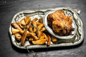 Fried chicken with potatoes on a tray. photo