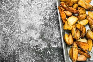 Fried potatoes on a baking tray with spices and herbs. photo