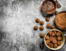 Chocolate truffles, cocoa powder and grated chocolate in bowls. photo