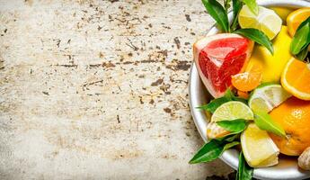 Sliced citrus fruits - grapefruit, orange, tangerine, lemon, lime leaves in a cup. photo