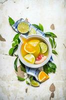 The juice from citrus fruits - grapefruit, orange, tangerine, lemon, lime in a cup with leaves. photo