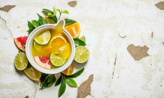 The juice from citrus fruits - grapefruit, orange, tangerine, lemon, lime in a cup with leaves. photo