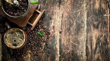 Fresh coffee in a clay mug with an old coffee grinder. photo