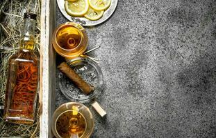 Cognac background. A bottle of cognac with lemon and a cigar. photo